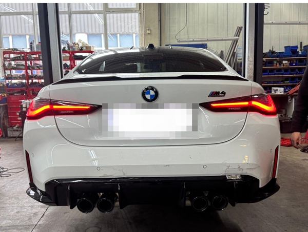 Weißes Coupé von hinten in einer Werkstatt