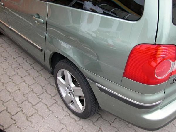 Schaden an der hinteren Seitenwand eines silbergrünen Vans